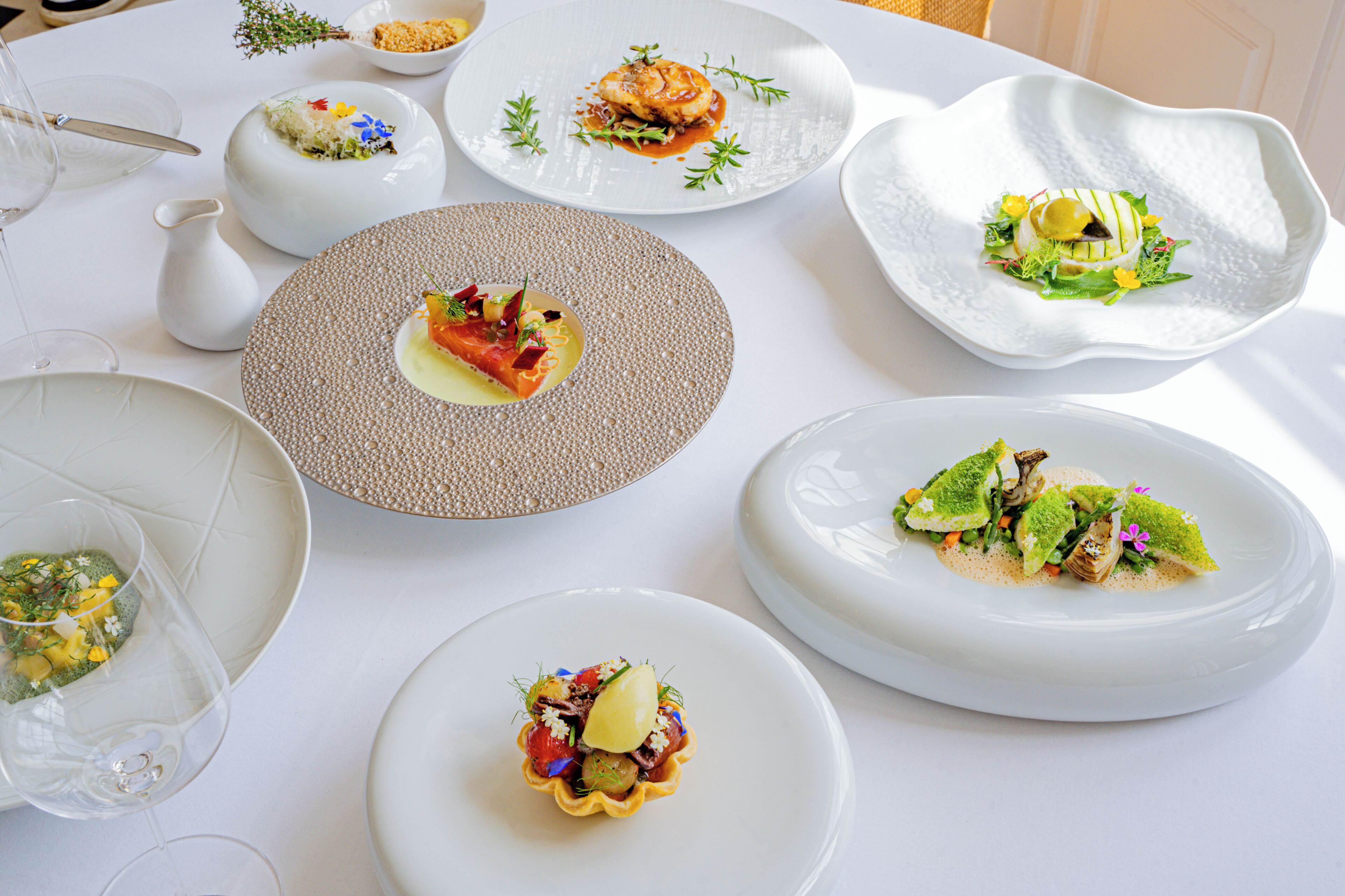 Une table dressée avec différents plats, des verres et une carafe.