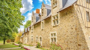 Un bâtiment en pierre doté de nombreuses fenêtres et d’un jardin à l’avant.