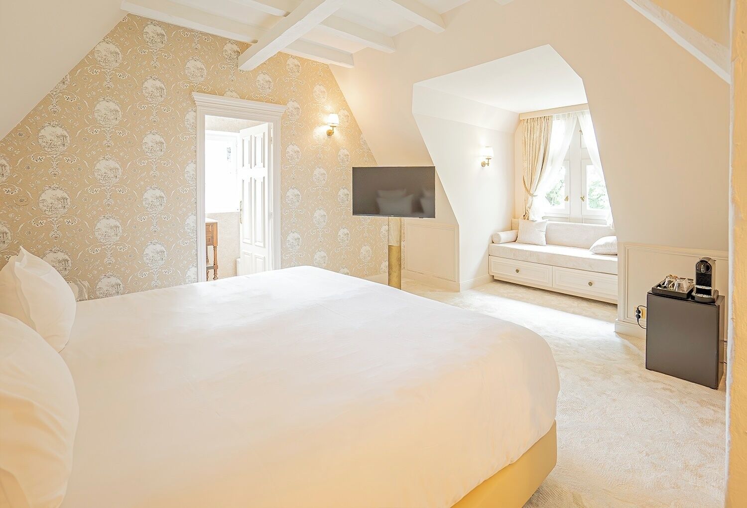 A bedroom with a large bed, a TV, a sofa, and a small table.