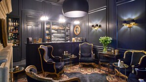 Un espace bar avec des lambris en bois foncé, un lustre et des tabourets de bar.