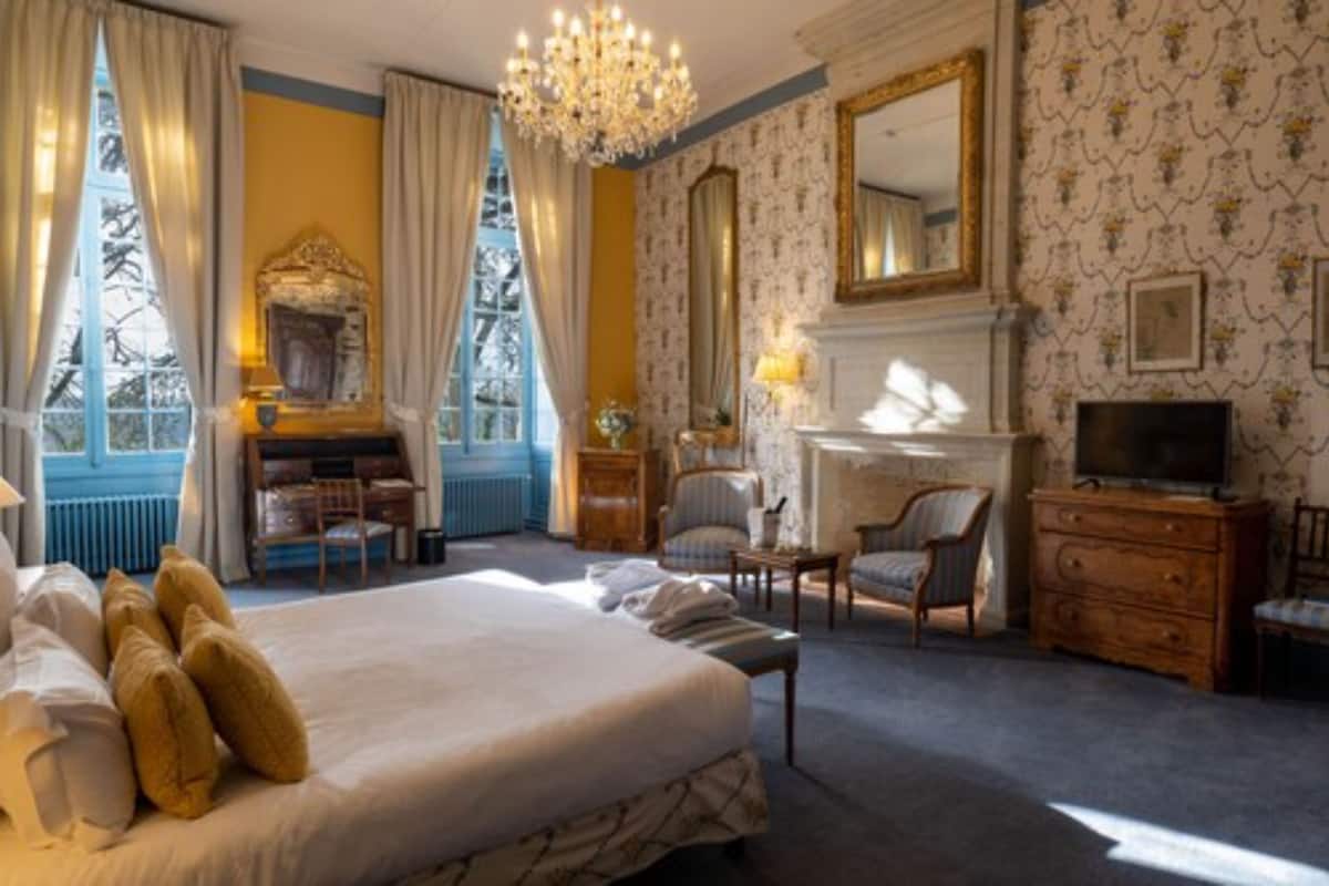Ein Hotelzimmer mit einem großen Bett, einem Kamin, einem Fernseher und einem Schreibtisch mit Stuhl.