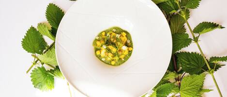 A white plate with a green dish in the center, surrounded by green leaves.