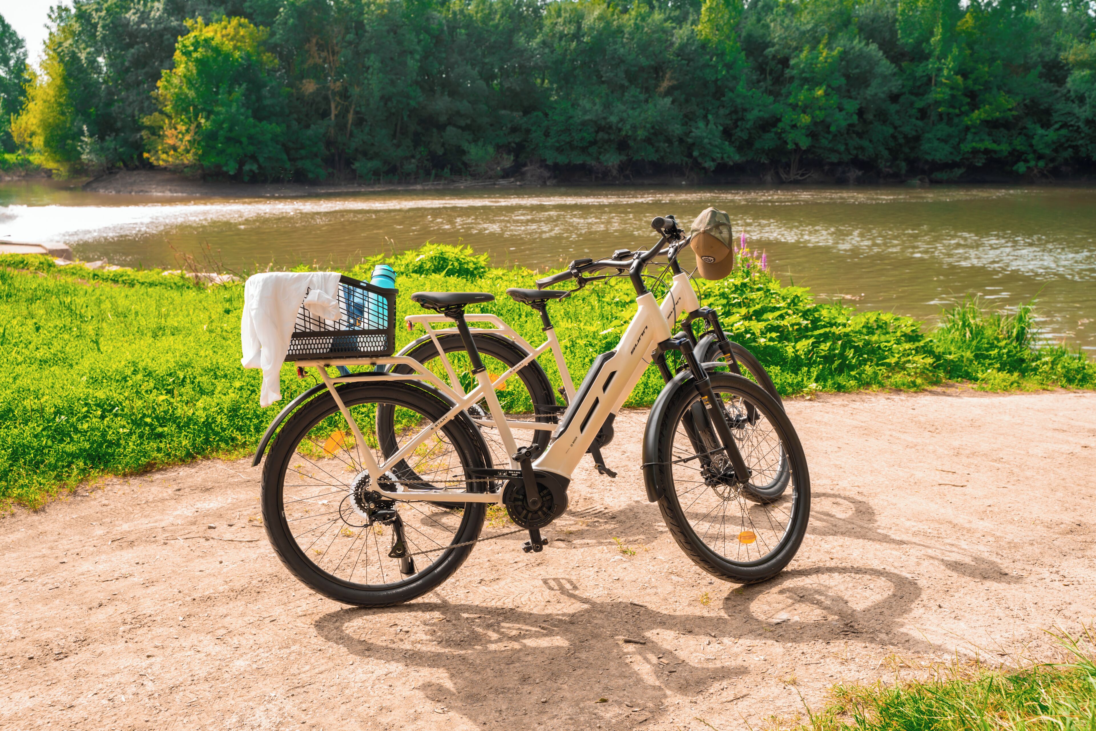 A bicycle parked on a dirt path with a river and greenery in the background.