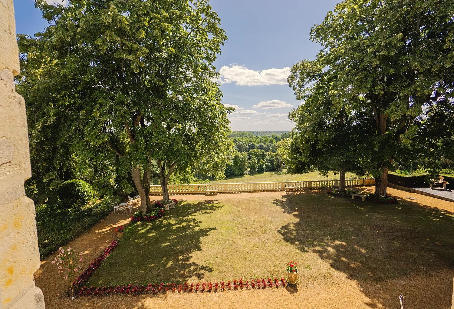 Un jardin bien entretenu, doté d’un chemin pavé, de bancs et offrant une vue sur le paysage environnant.