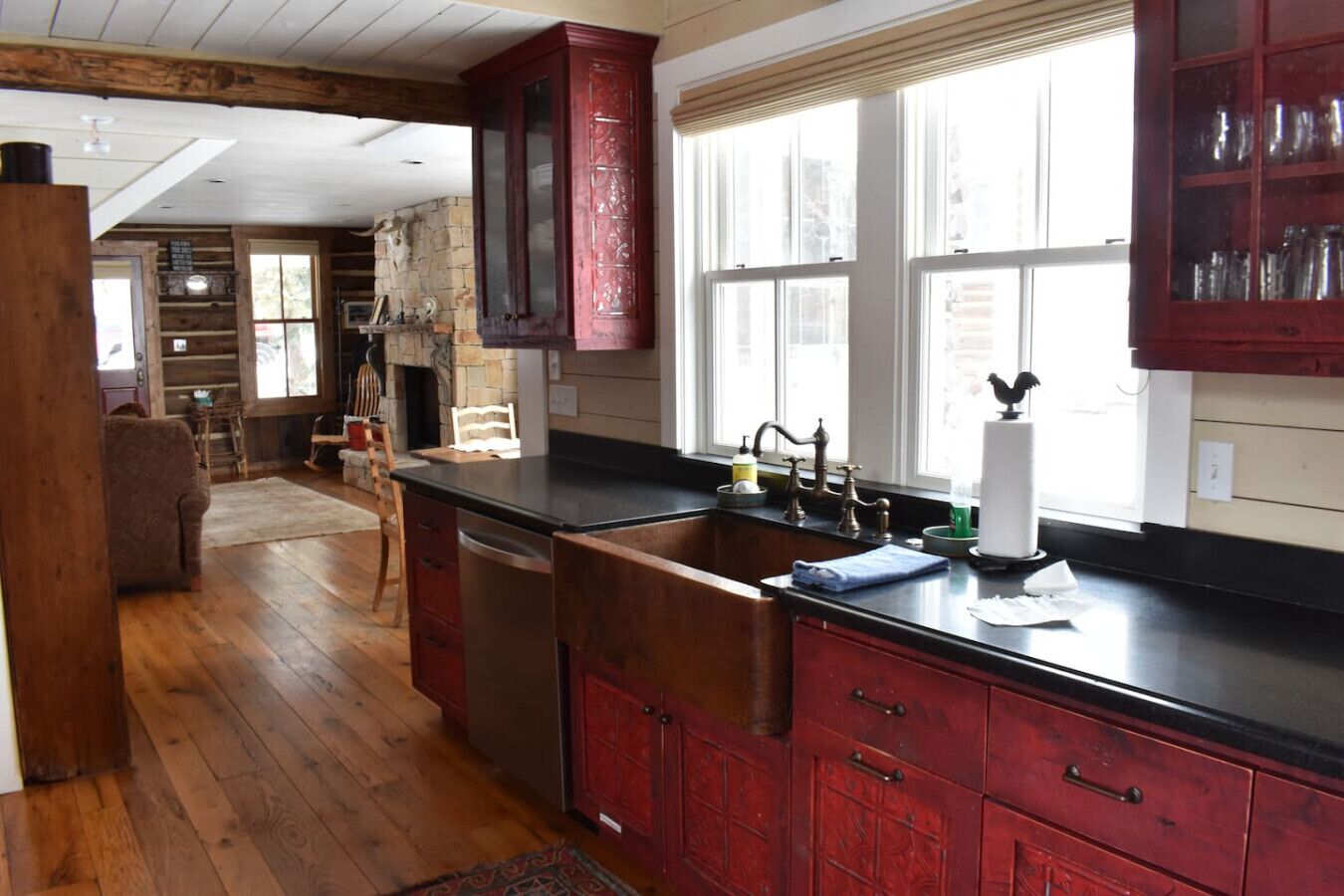 A kitchen with wooden cabinets, a black countertop, and a stone fireplace.