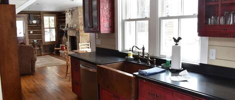 A kitchen with wooden cabinets, a black countertop, and a stone fireplace.