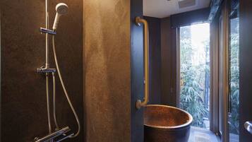 A modern bathroom with a shower, a handrail, and a large copper basin.