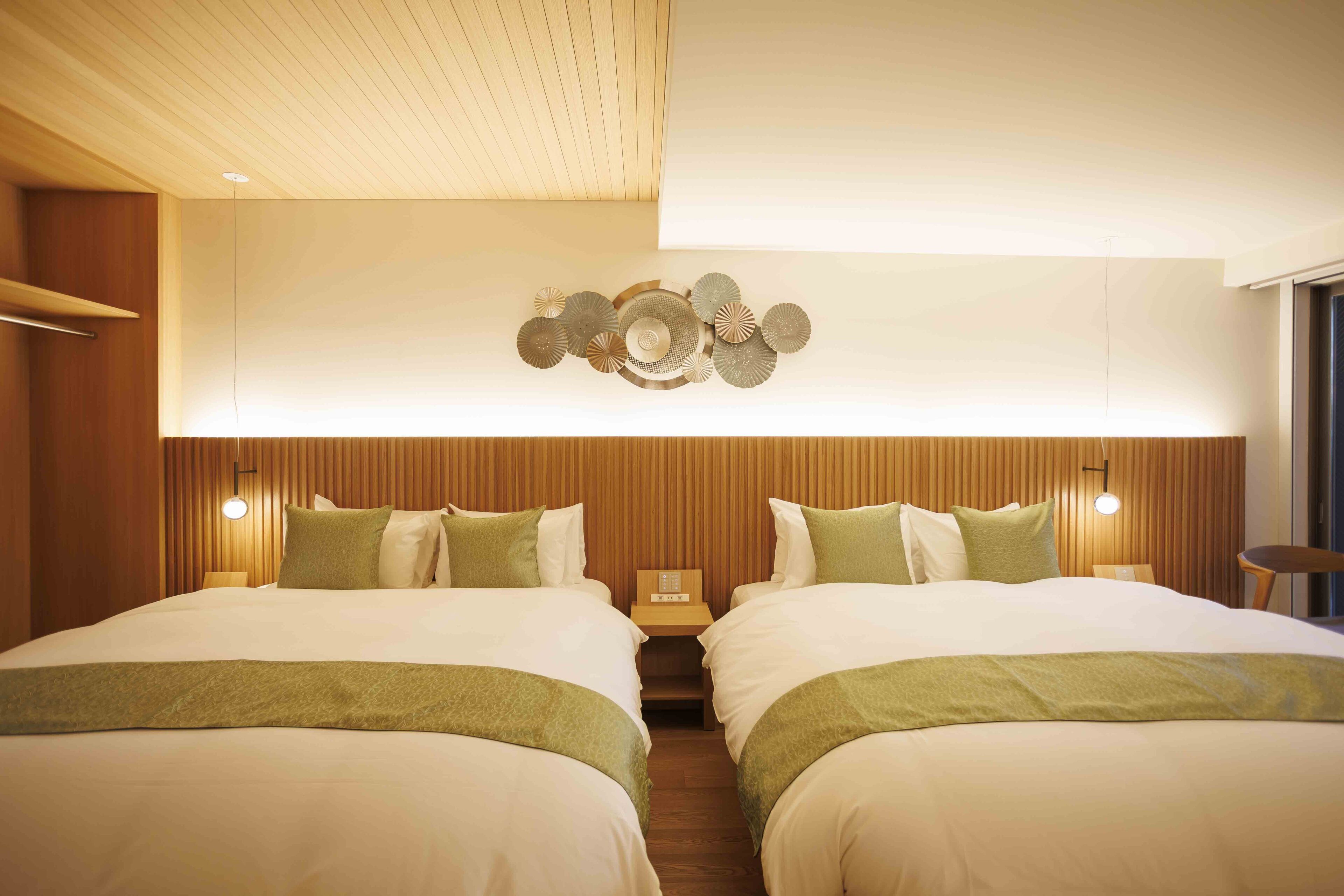 A hotel room with two beds, wooden paneling, a decorative wall piece, and bedside lamps.