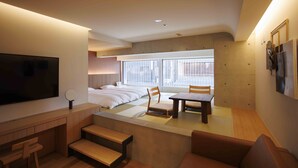 Een moderne hotelkamer met een groot bed, een bureau, een stoel, een klein tafeltje en een televisie.