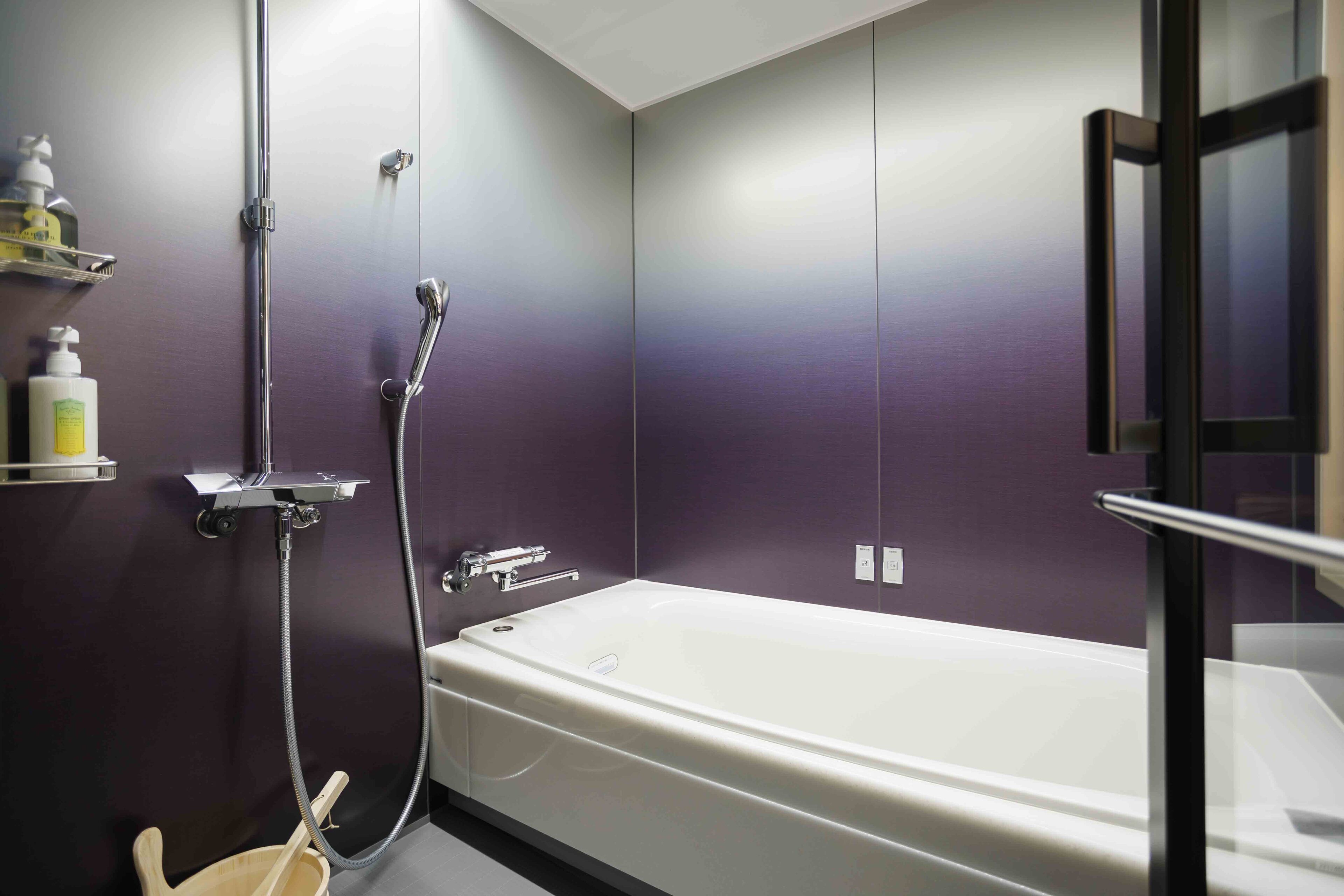 Un baño moderno con bañera, ducha e inodoro con mampara de vidrio.