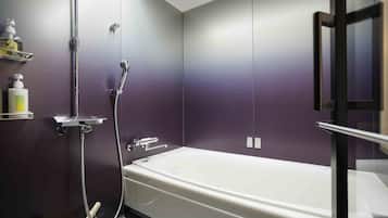 Un baño moderno con bañera, ducha e inodoro con mampara de vidrio.