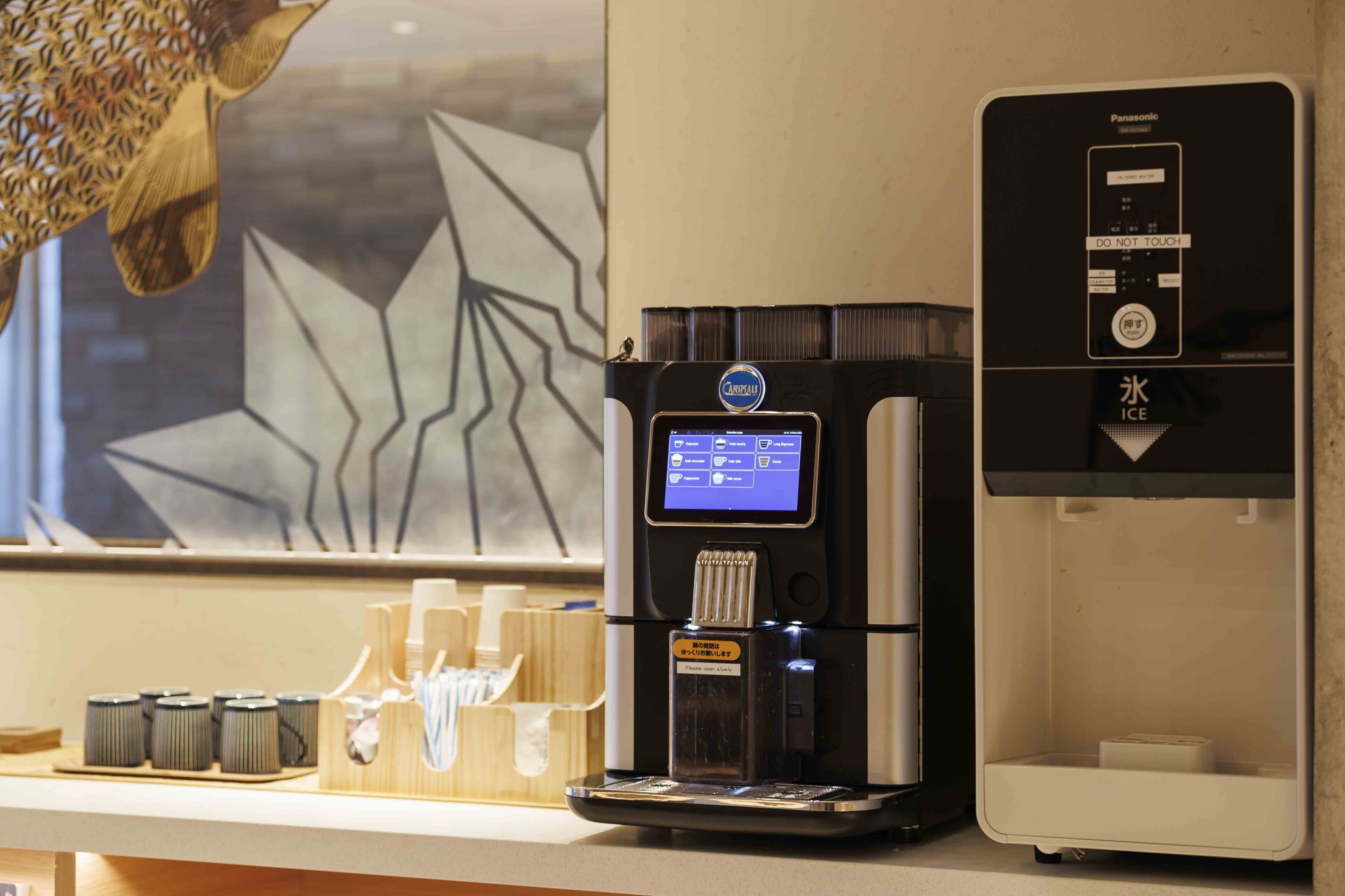 A coffee machine with a digital display, a water dispenser, and a coffee cup holder with disposable cups.