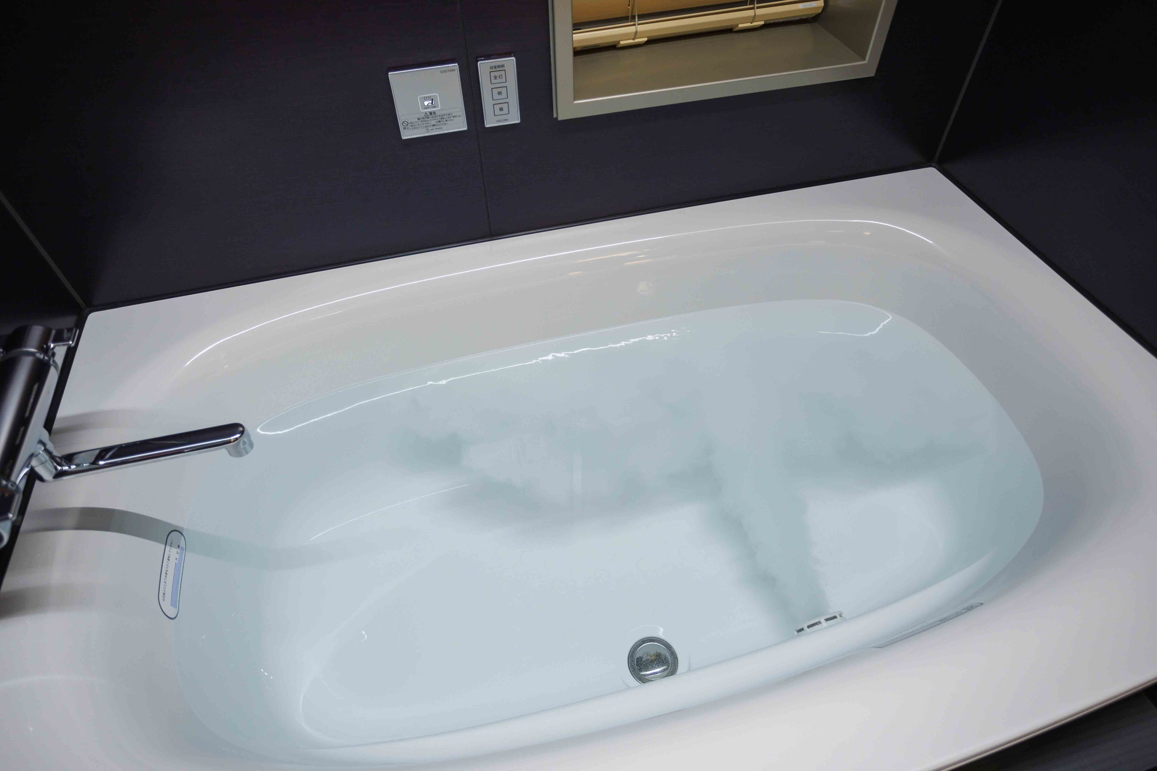 Un baño moderno con una bañera blanca, un grifo cromado y un panel de control por encima de la bañera.