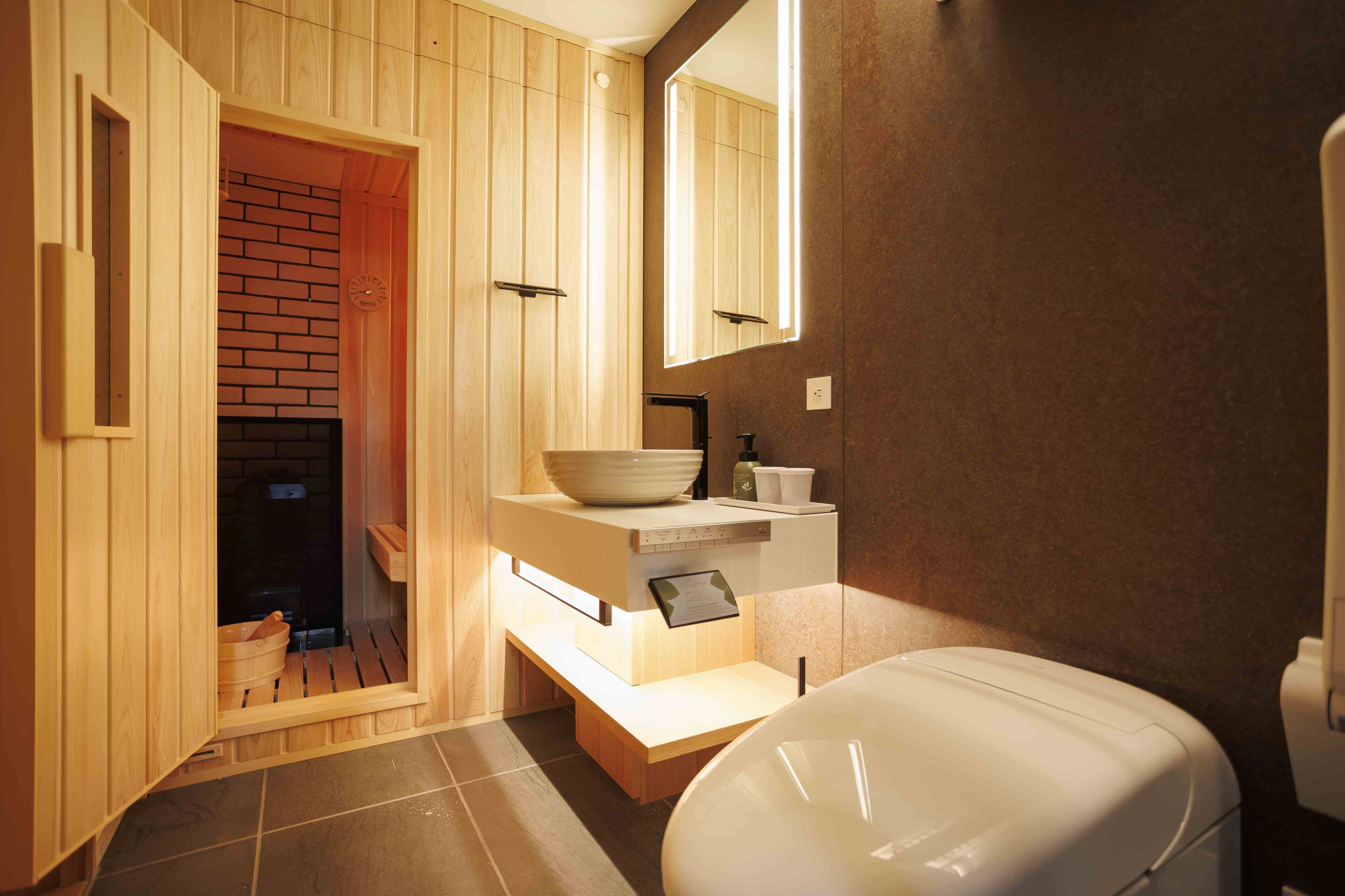 A modern bathroom with a wooden sauna, a large mirror, and a white toilet.