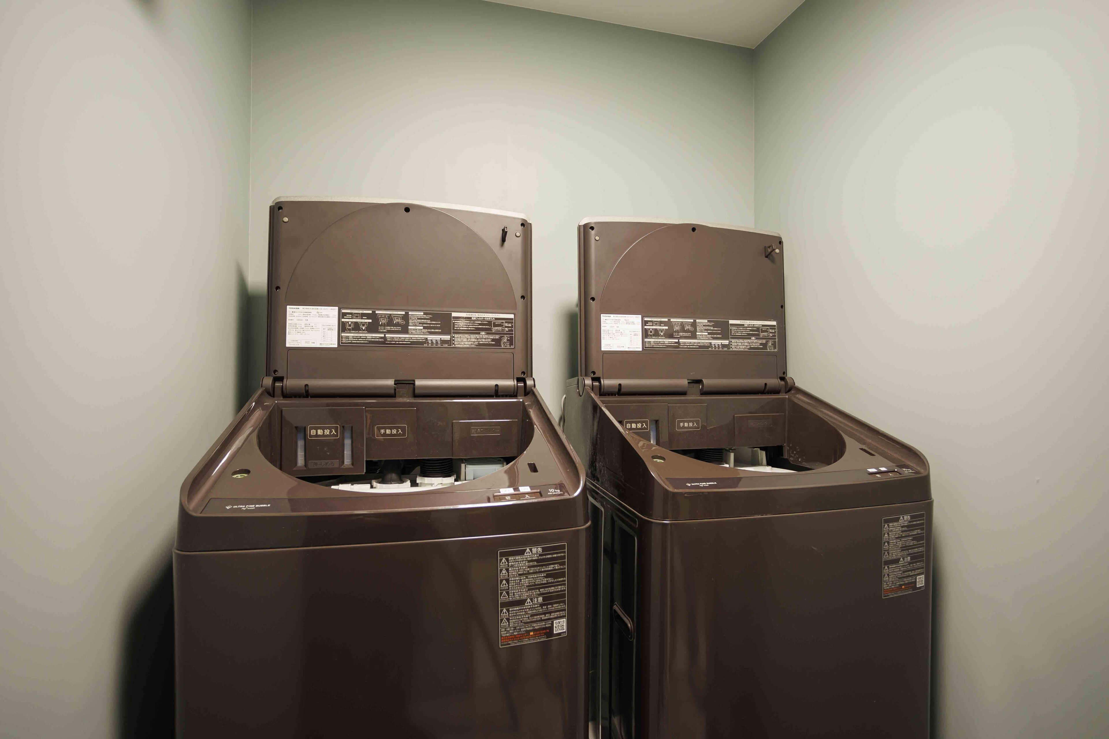 Two brown, compact, wall-mounted laundry machines in a room with light-colored walls.