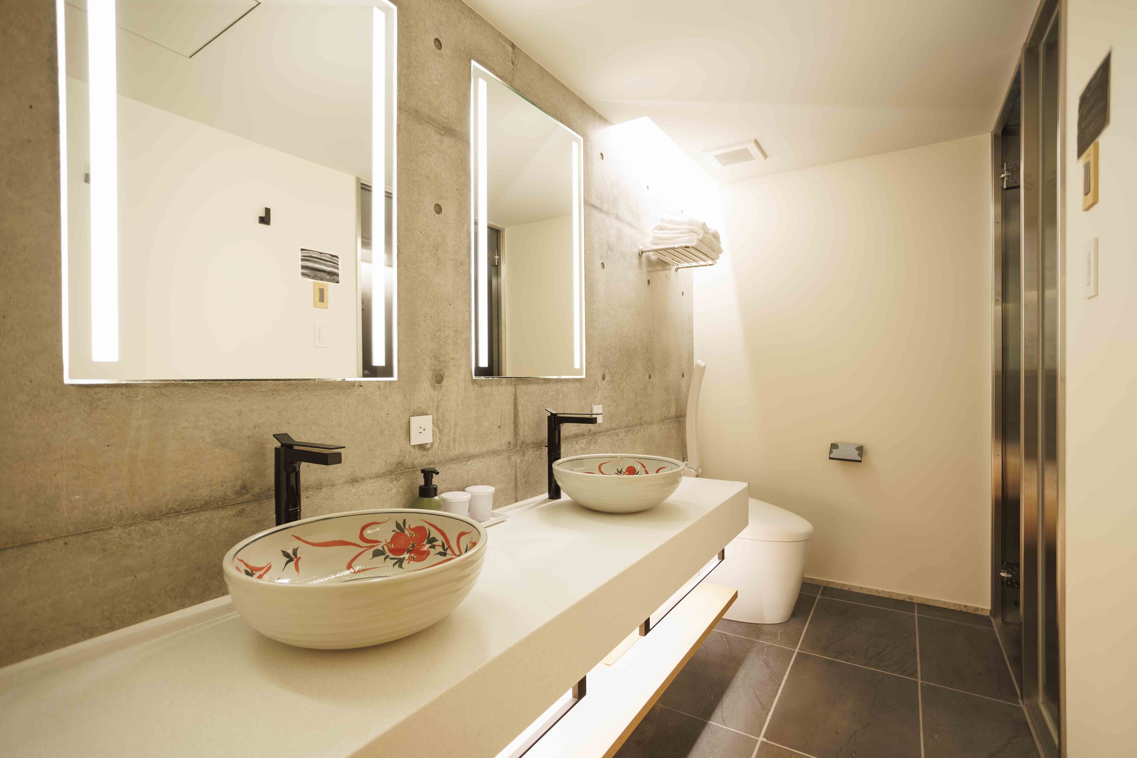 A modern bathroom with two sinks, a large mirror, and a shower area.