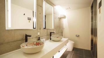 A modern bathroom with two sinks, a large mirror, and a shower area.