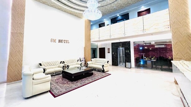 A hotel lobby with a seating area, a chandelier, and a visible reception desk. - HOTEL SM RAINBOW INTERNATIONAL (Hyderabad)