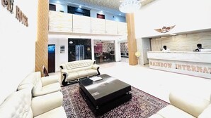 A hotel lobby with a reception desk, a chandelier, and a seating area with sofas and a coffee table. - HOTEL SM RAINBOW INTERNATIONAL (Hyderabad)