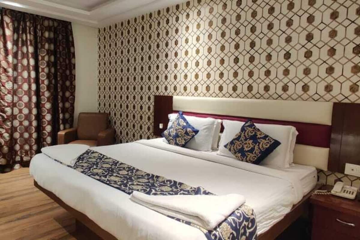 Une chambre d’hôtel avec un grand lit, un bureau, une chaise et un mur décoré d’un motif.