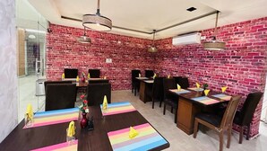 A restaurant with brick walls, wooden tables, and chairs. - HOTEL SM RAINBOW INTERNATIONAL (Hyderabad)
