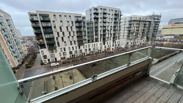 Un bâtiment moderne doté de nombreux balcons, d’une terrasse en bois et offrant une vue sur la rue en contrebas.