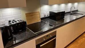 Une cuisine moderne équipée d’une cuisinière intégrée, d’un grille-pain, d’une bouilloire et d’un évier.
