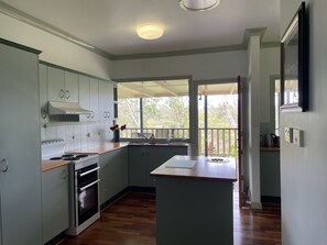 A kitchen with a wooden countertop, a built-in oven, and a view of the outdoors through a large window.
