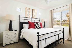 Un dormitorio con cama, mesitas de noche, una ventana con cortinas y decoración en la pared.
