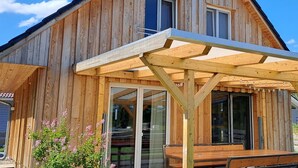 A wooden building with a covered patio area and large windows. - Dogs and children welcome, 150m to the beach, fenced property,  (Rheinsberg OT Flecken Zechlin)