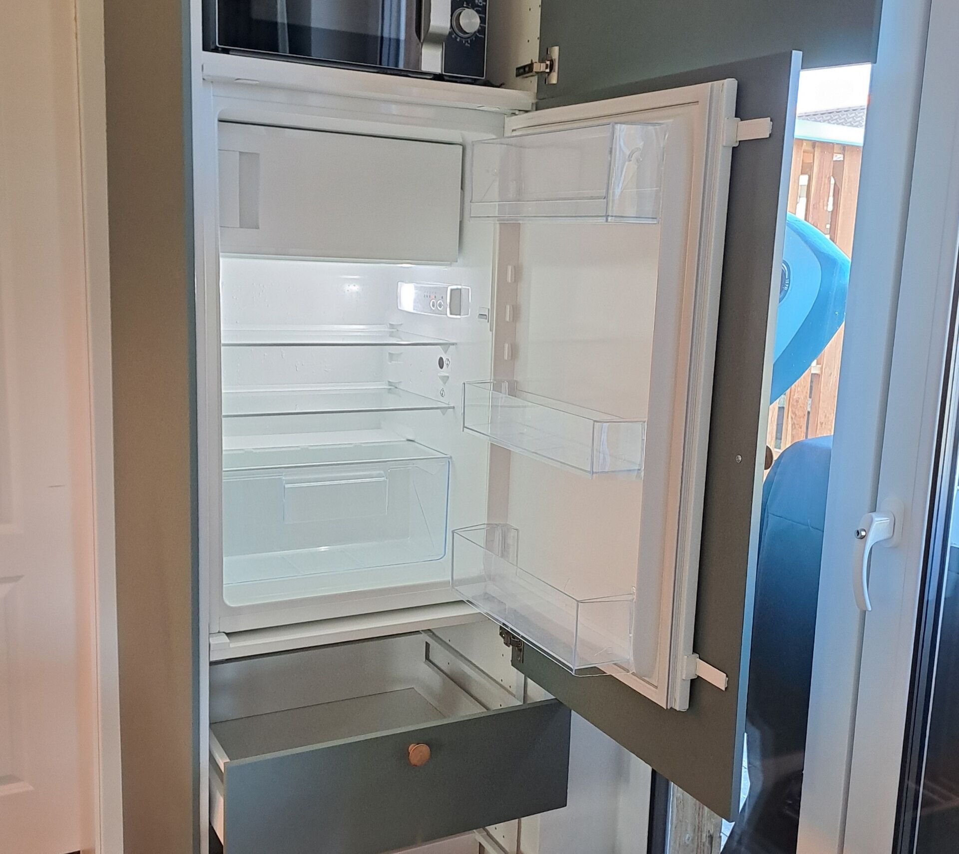 Ein offener Kühlschrank mit mehreren Ablagen und einem Gefrierfach.