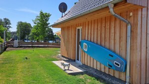 A wooden building with a satellite dish, a blue kayak, and a dog in the yard. - Dogs and children welcome, 150m to the beach, fenced property,  (Rheinsberg OT Flecken Zechlin)