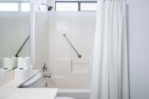 A modern bathroom with a walk-in shower, a handrail, and a toilet paper holder. - 4BR Pool, Spa & Retro Arcade Polished Vegas Stay (North Las Vegas)