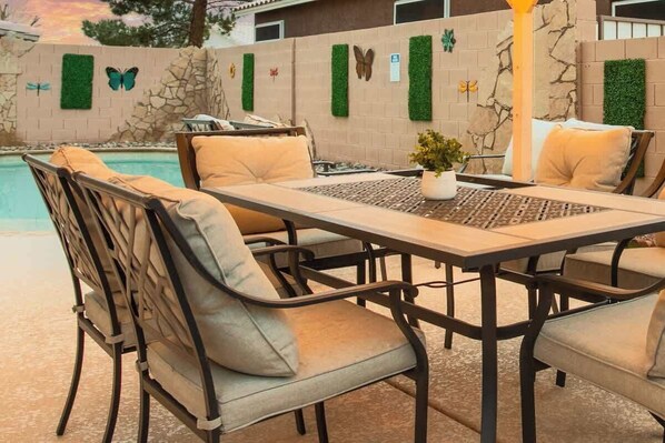 A poolside patio with a table and chairs, surrounded by decorative walls with butterfly motifs.