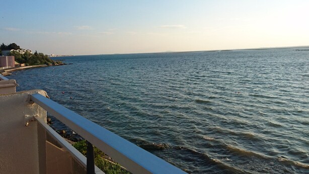 A coastal view with a balcony overlooking the sea, a distant shoreline with buildings, and a clear sky. - T2 Apartment in Balaruc-les-Bains, view of the pond, air-conditioned, private parking, WiFi (Balaruc-les-Bains)