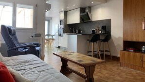 A modern living room with a sofa, a coffee table, and a dining area with chairs. - T2 Apartment in Balaruc-les-Bains, view of the pond, air-conditioned, private parking, WiFi (Balaruc-les-Bains)