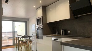 A modern kitchen with a dishwasher, oven, and microwave. There is a dining area with a table and chairs. - T2 Apartment in Balaruc-les-Bains, view of the pond, air-conditioned, private parking, WiFi (Balaruc-les-Bains)