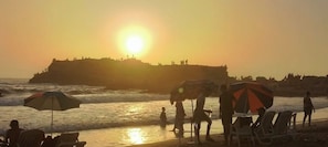 A beach scene with people, umbrellas, and chairs.