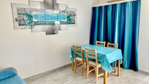 Een eetruimte met een tafel bedekt met een blauwe tafelkleed, houten stoelen en een blauw gordijn.