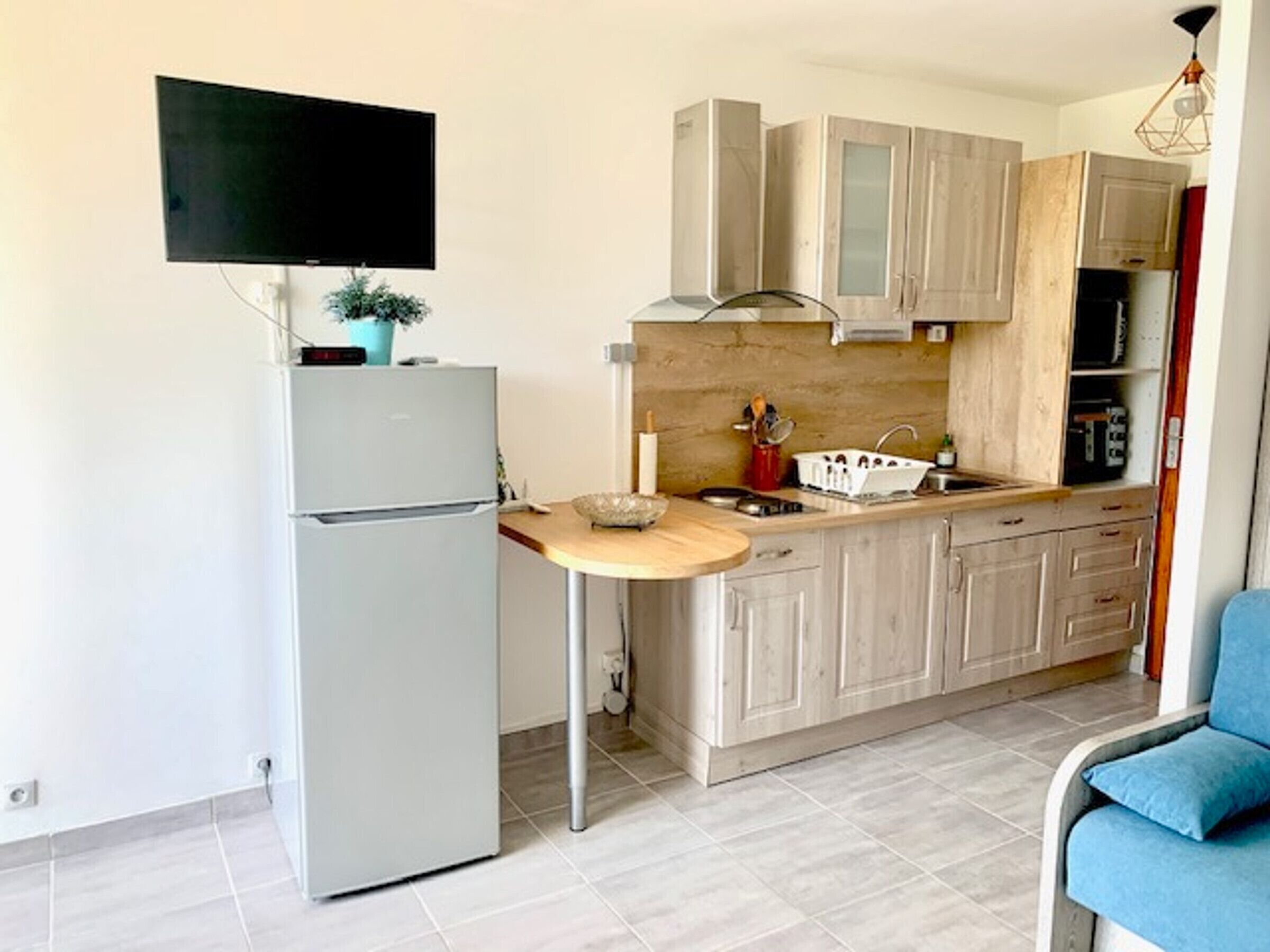 Una cocina compacta con refrigerador integrado, encimera de madera y pileta.