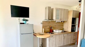 Een kleine keuken met een geïntegreerde koelkast, een houten aanrechtblad en een spoelbak.