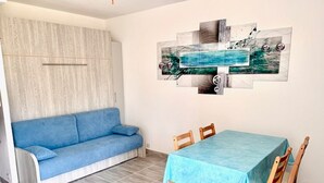 Een kamer met een blauwe bank, een tafel met een blauwe tafelkleed, en een wand met een decoratief kunstwerk.