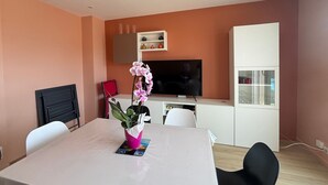 A modern living room with a dining table, chairs, a TV, and a cabinet. - Renovated 2BR Apartment, Sleeps 5, City Center, Close to Beach, Parking, WiFi (Les Sables-d'Olonne)