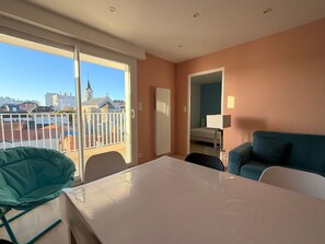 A hotel room with a balcony, a bed, a sofa, and a table. - Renovated 2BR Apartment, Sleeps 5, City Center, Close to Beach, Parking, WiFi (Les Sables-d'Olonne)