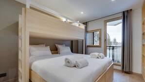 A modern hotel room with a wooden bunk bed, a large window with a view, and a balcony. - Renovated apartment at the slopes, pets allowed (Val-d'Isère)