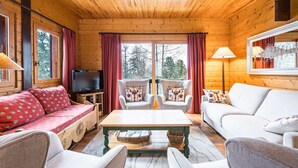 A cozy log cabin interior with a sofa, chairs, a television, and a table. - Cozy chalet near slopes with Wifi (La Plagne)