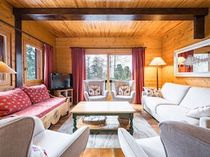 L’intérieur d’un chalet confortable, avec un canapé, des fauteuils, un téléviseur et une table.