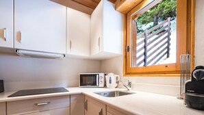 A kitchen with white cabinets, a microwave, a kettle, and a sink. - Cozy chalet near slopes with Wifi (La Plagne)
