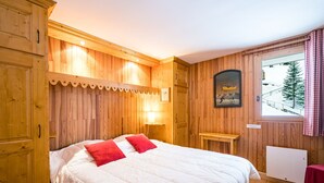 A wooden-paneled room with a bed, a window with a view of a snowy landscape, and a framed picture on the wall. - Cozy chalet near slopes with Wifi (La Plagne)