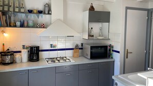 Eine kompakte Küche mit Gasherd, Mikrowelle und einem kleinen Schrank über der Arbeitsfläche.